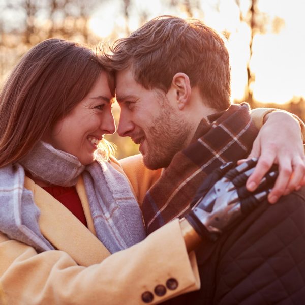 Portrait Of Romantic Couple With Woman With Prosthetic Hand Hugging in Winter Or Autumn Countryside